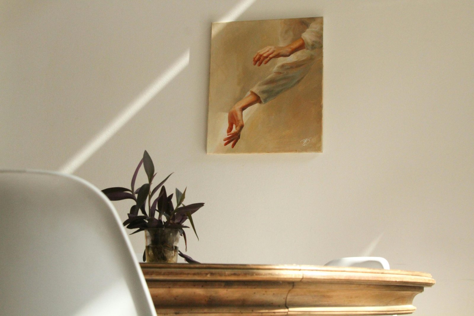 A serene minimalist room featuring a painting, wooden table, and potted plant.